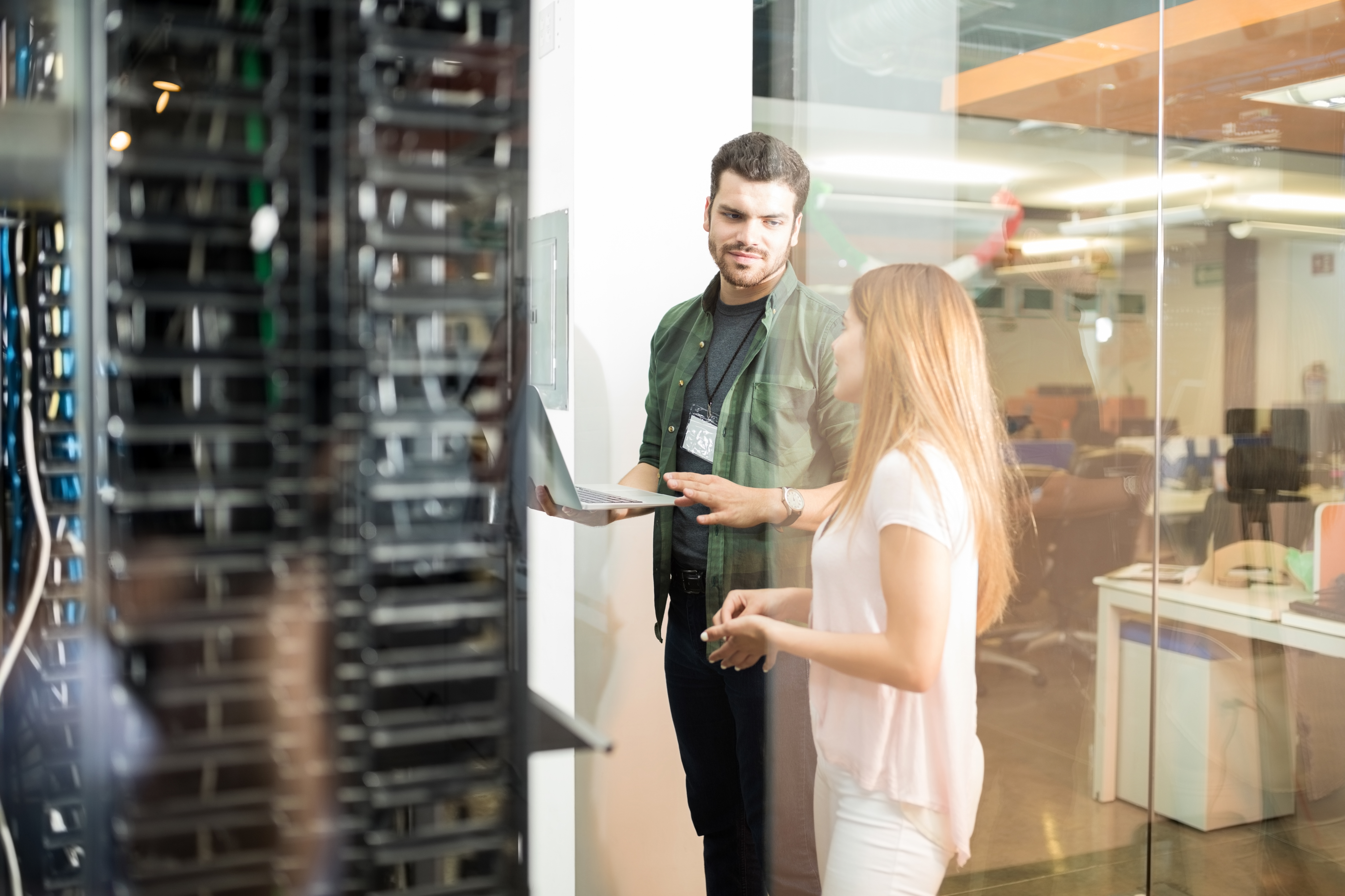 two_business_people_standing_server_room_with_laptop_discussing.jpg